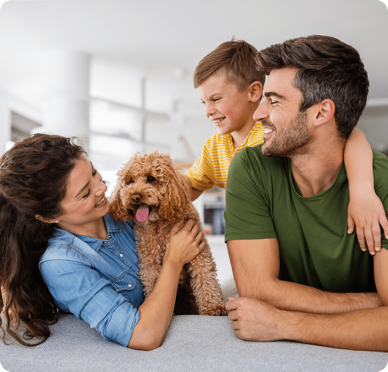 Family smiling with dog in living room.
