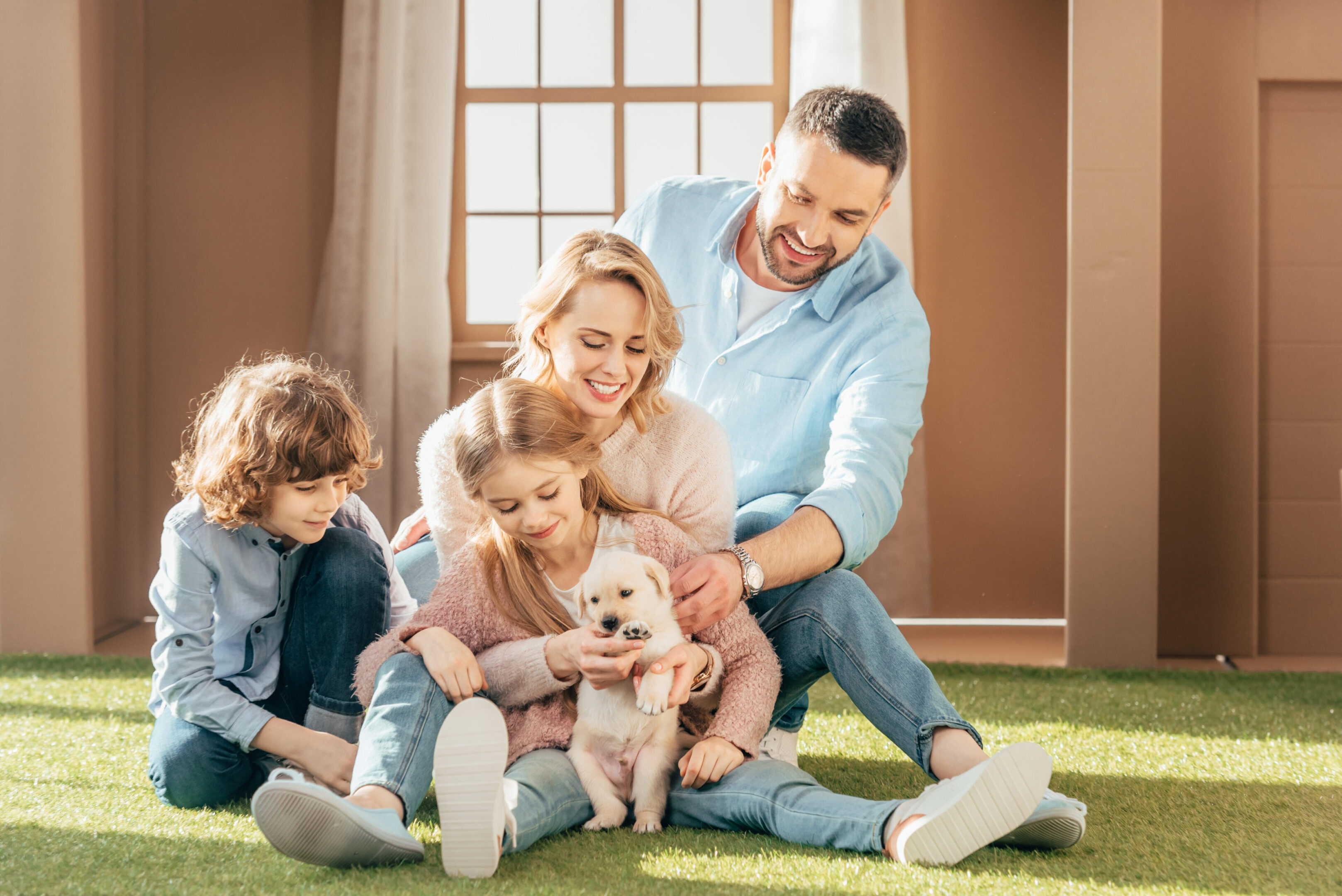 Family sitting on grass with small puppy.